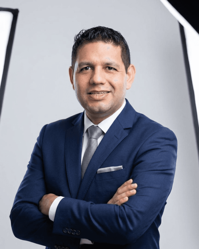 Dr. Deivid Santos, de terno azul-marinho, com os braços cruzados
